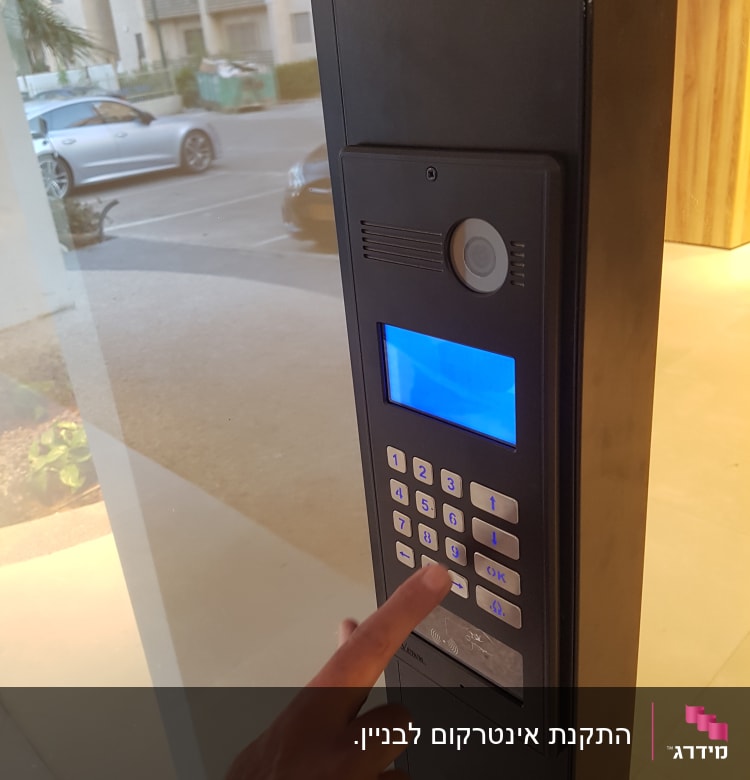 אדם לוחץ על מקשי אינטרקום עם מסך כחול